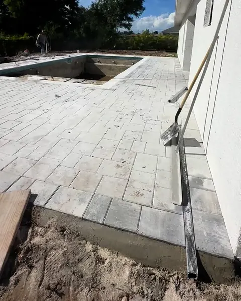 New pavers being laid around a pool beside a house