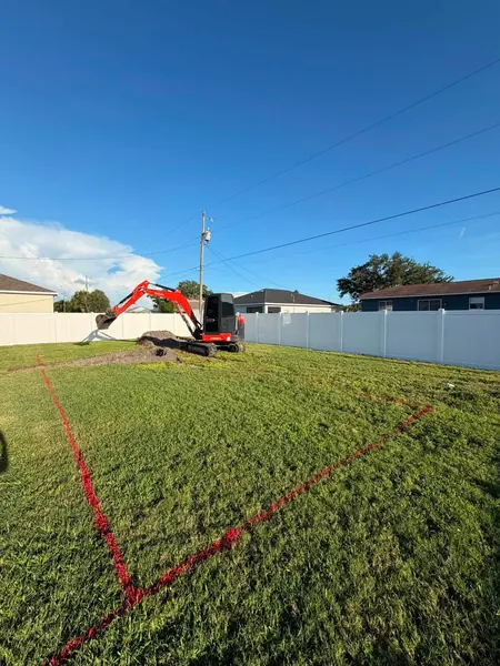 A pool outline painted on the grass with a mini excavator starting to dig